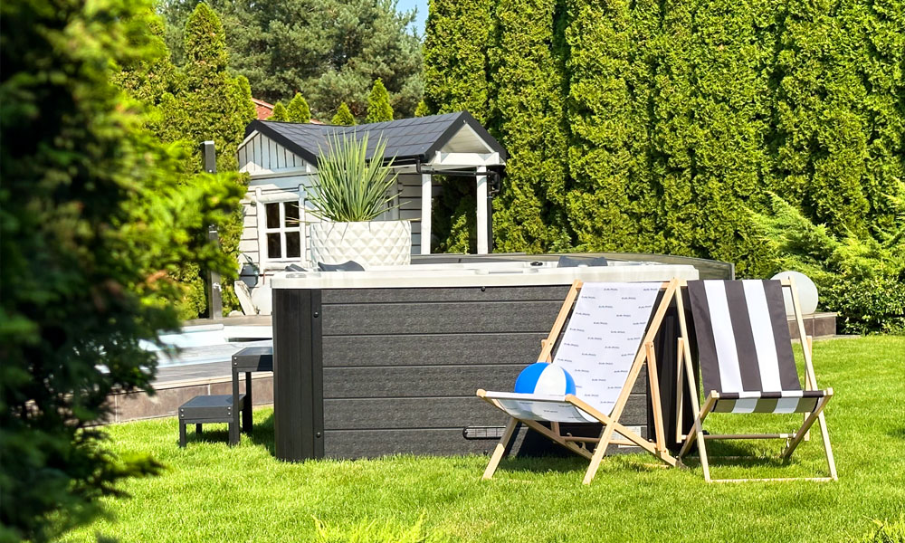 Garten mit Whirlpool, gestreifter Liegestuhl und Ball, von Bäumen umgeben, bei sonnigem Wetter.