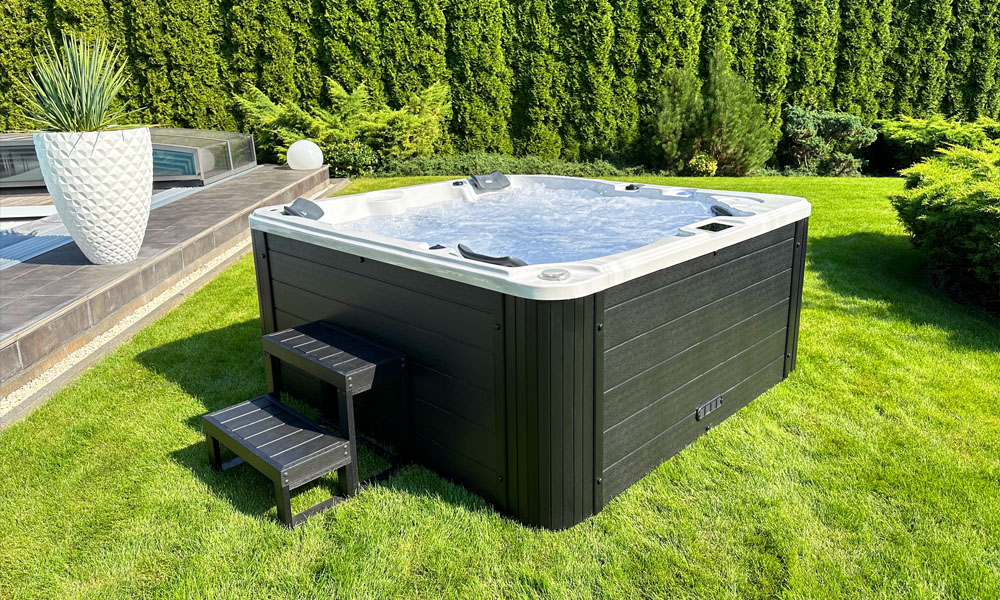 Whirlpool im Garten mit klar sprudelndem Wasser, dunkler Holzoptik und umgeben von grünen Pflanzen.
