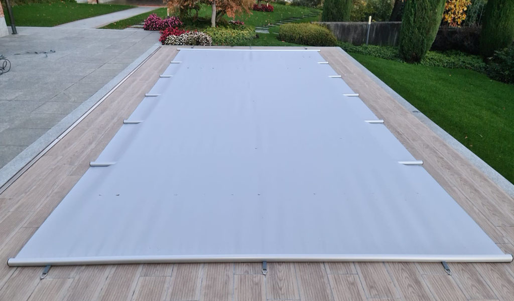 Eine weiße Terrassenabdeckung mit Holzdeck in einer gepflegten, grünen Gartenumgebung.