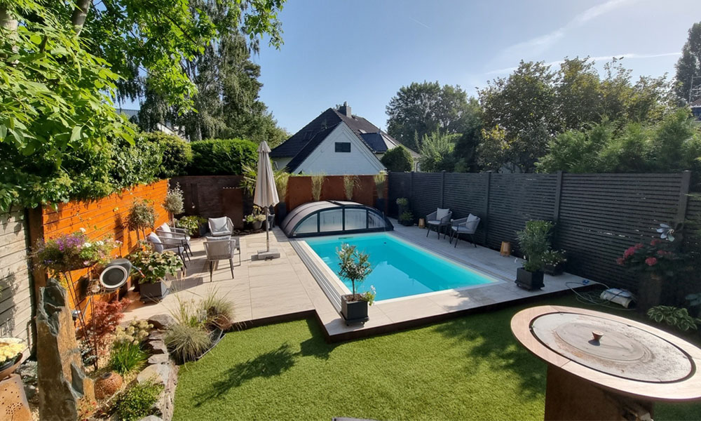 Ein moderner Garten mit kleinem Pool, viel Grün und gemütlichen Sitzbereichen.