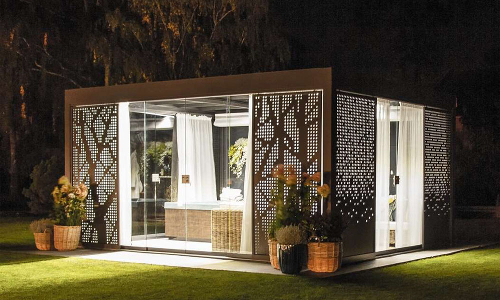 Ein modern beleuchteter Pavillon mit dekorativen Seitenelementen im Garten bei Nacht.