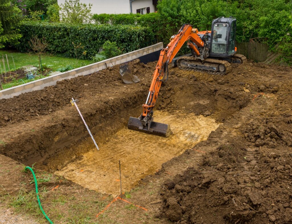 Bagger gräbt Loch für den Pool